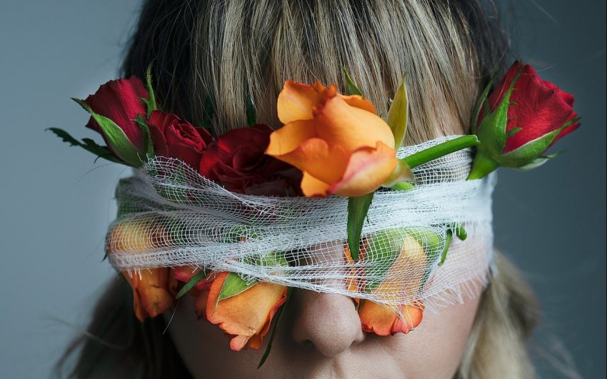 Unrecognizable woman with blindfold and blooming roses
